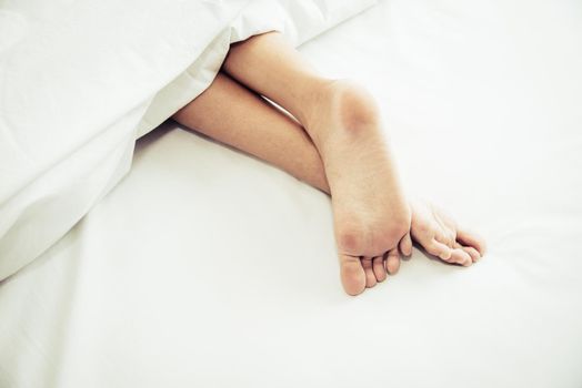 Barefoot of human on bed in morning. Single and Working people concept. Lazy day and Happiness home theme.