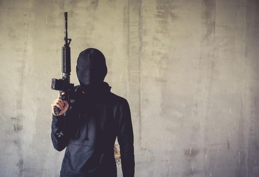 Terrorist holding rifle gun on grunge wall. Social issued theme. Terrorist and Robber concept. Police and Soldier theme. Social issued theme.