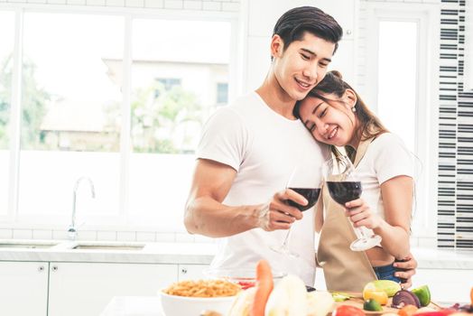 Asian lovers or couples drinking wine in kitchen room at home. Love and happiness concept Sweet honeymoon and Valentine day theme