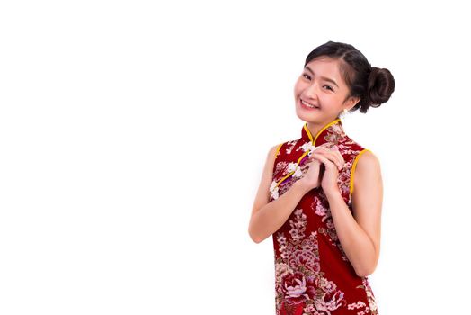 Young Asian beauty woman wearing cheongsam and blessing or greeting gesture in Chinese new year festival event on isolated white background. Holiday and Lifestyle concept. Qipao dress wearing