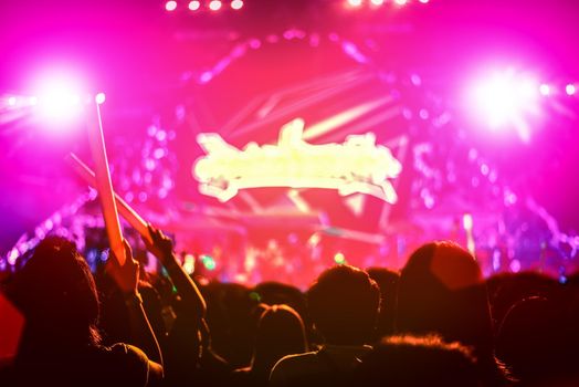 Rock concert with silhouettes people in happy gesture and raising up hands for cheer up singer. Entertainment and People concept. Singer and Audience theme. Purple and Red pink tone