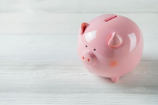Pink Piggy bank on white wood floor. Financial and money savings concept. Copy space