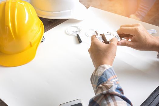 Construction engineer measuring with vernier caliper. Business and Technology concept. Safety helmet and Drawing paper elements. Civil and Drawing sketch theme.