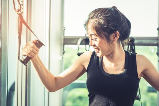 Asian young woman doing elastic rope exercises at cross fitness gym. Strength training and muscular Beauty and Healthy concept. Sport equipment and Sport club center theme. 