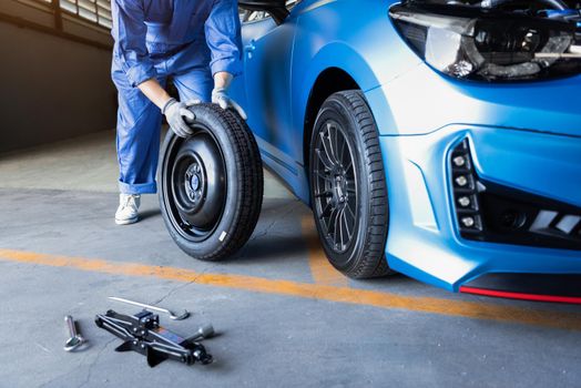 Car mechanics changing tire at auto repair shop garage. Transportation and Business working people concept. Automobile technician maintenance vehicle by customer claim order. Wheel repair service