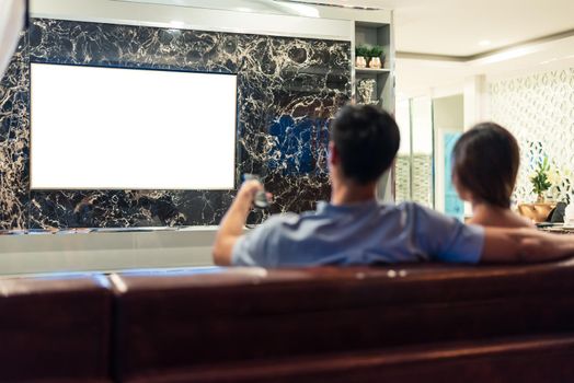 Asian couples watching white blank screen display television for advertising template background.  People lifestyles concept. Lockdown social distancing work from home. Selective focus on TV