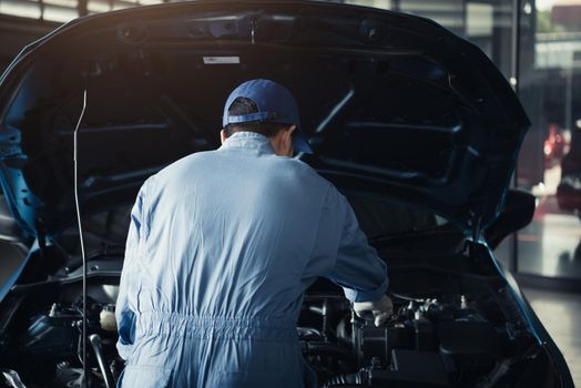 Car mechanic opening car hood for internal checking to maintenance vehicle by customer claim order in auto repair shop garage. Engine repair service. People occupation and job. Automobile technician