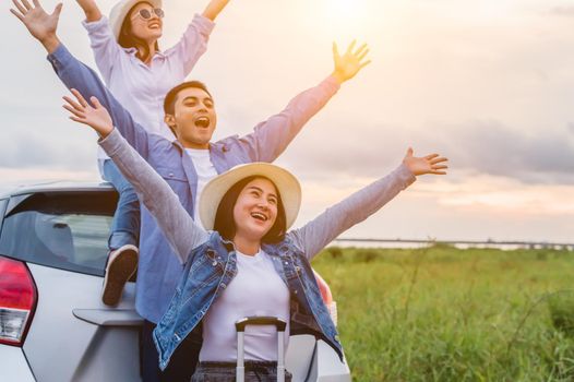 Happy Asian friends spread arms widely and breathed fresh air with happiness mood in on raod trip in car trunk. People lifestyle in long vacation trip concept. Outdoors nature and transportation