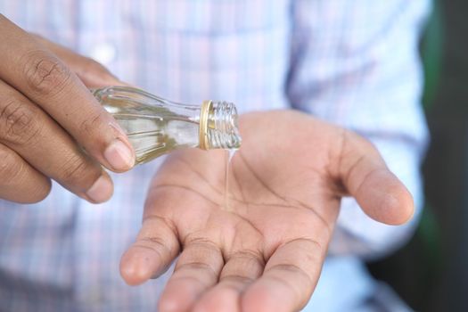 pouring hair oil on hand close up .