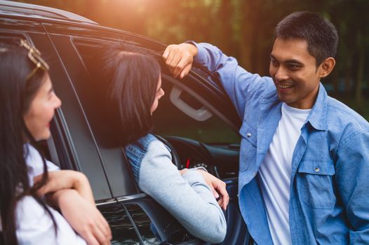 Asian man flirting women in car during travel in forest. Boy talking to girls for meeting. People lifestyles and weekend tour concept. Summer and nature theme. Mountain camping people group in holiday