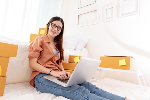 Beauty Asian woman using laptop for customer support in bedroom. Business Technology concept. Delivery online shopping. Service. People lifestyle remote work in domestic house. Looking at camera