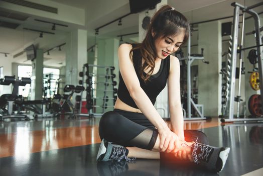 Asian woman injuries during workout at knee in fitness gym sport center. Medical and Healthcare concept. Exercise and Training theme. People healthy lifestyle and leisure activity problem