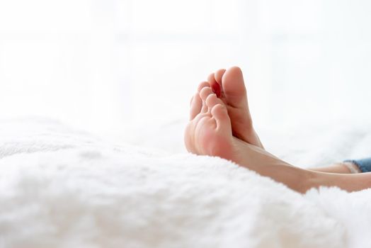 Closeup woman feet skin wearing jeans on white bed. Healthcare and health medical concept.