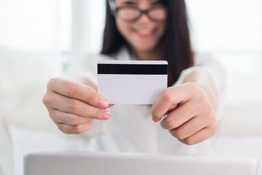 Young Asian woman use credit card for online shopping with laptop. Business and Banking payment concept. Price sale and promotion concept. Technology and Computer theme. E-commerce and Marketing theme