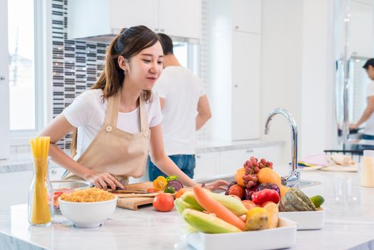 Asian lovers or couples preparing and looking for necessary ingredients in kitchen with full of ingredient on table. Honeymoon and Happiness concept. Valentines day and Sweet home concept