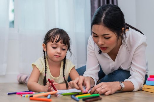 Mother teaching girl in drawing class. Daughter painting with colorful crayon color in home. Teacher training students in art classroom. Education and development of kid theme. Learn from home