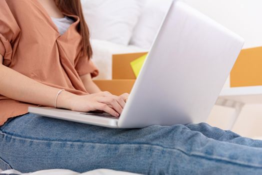 Closeup of laptop using by woman for online shopping delivery business at home. Girl typing on keyboard by hand. People lifestyle and occupation concept. Entrepreneur work from home and shop owner