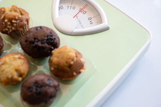 Closeup of weight scale with delicious  fat and sweet bread flavor on top. Like calories that cause weight gain a lot. Health and Beauty concept. Diet and Healthcare. Overweight and Fitness