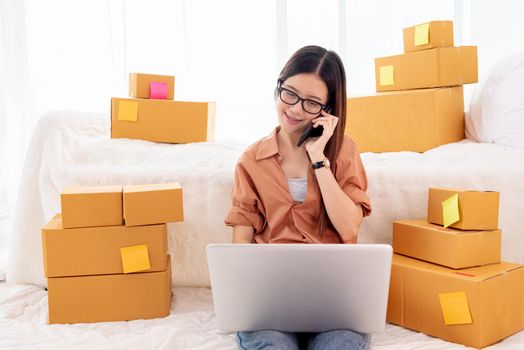 Beauty Asian woman using laptop and calling phone on bed. Business and Technology concept. Delivery and Online shopping concept. Post and Service theme. People lifestyle remote work in domestic house