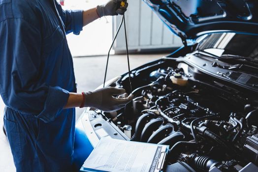 Car mechanic holding checking gear oil to maintenance vehicle by customer claim order in auto repair shop garage. Engine repair service. People occupation and business job. Automobile technician