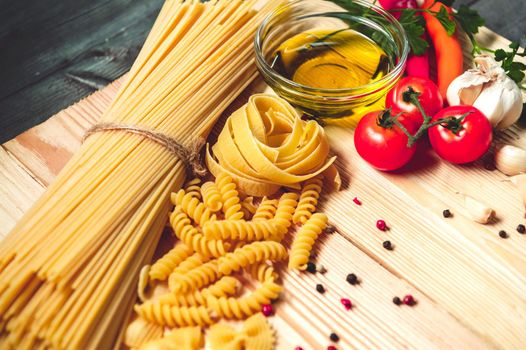 Tasty appetizing italian spaghetti pasta ingredients for kitchen cuisine with tomato, cheese parmesan, olive oil, fettuccine and basil on wooden brown table. Food Italian recipe homemade. Top view