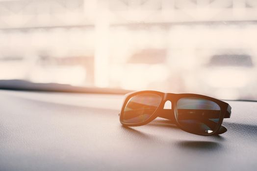 Black sunglasses on the front console of car on traveling. Soft and split cross processing tone to retro vintage pinterest and instragram like process.