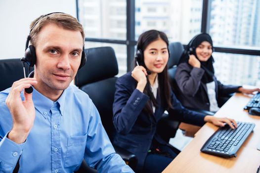 Group of young profession call center operator agent with headsets working in office. Business telemarketing service people concentrating on having conversation work and talking to customer friendly