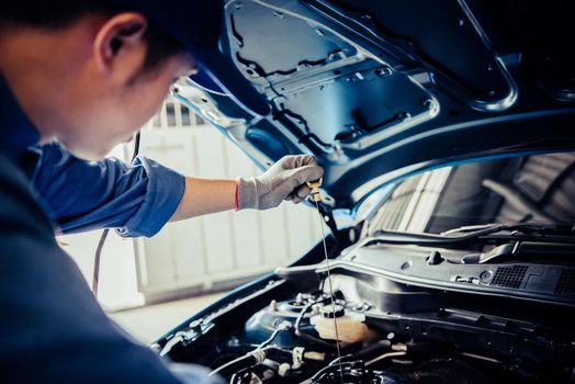 Car mechanic holding checking gear oil to maintenance vehicle by customer claim order in auto repair shop garage. Engine repair service. People occupation and business job. Automobile technician