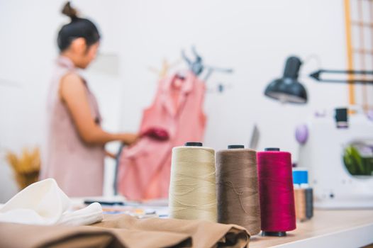 Closeup of colorful thread with fashion designer background in workshop studio. Stylish fashionista woman creating new cloth design collection. Tailoring and sewing People lifestyle and occupation