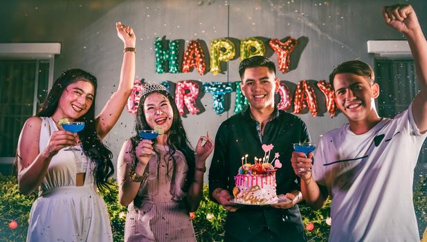 Asian friends having fun in outdoor birthday party at night club with birthday cake. Event and anniversary concept. People lifestyles and friendship. Group of young adult celebrating and anniversary