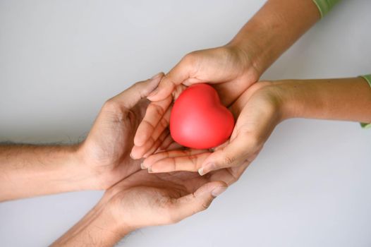 Closeup of Helping hand of heart donor for patient in heart disease. Man give red heart to woman as couple. People lifestyle and couple romance. Healthcare and hospital medical concept