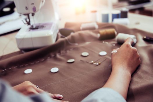 Dressmaker designing new fashion dress fabric with sewing machine. Fashion designer tailor or sewer in workshop studio designing new collection cloth. Business owner and entrepreneur. Selective focus