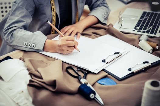 Closeup of attractive female fashion designer hand working in home office workshop. Stylish fashionista woman creating new cloth design collection. Tailoring and sewing People lifestyle and occupation