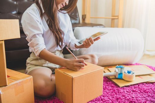 Asian business woman startup small business entrepreneur SME distribution warehouse with parcel mail box. small owner home office. Online marketing and product packaging and delivery service concept