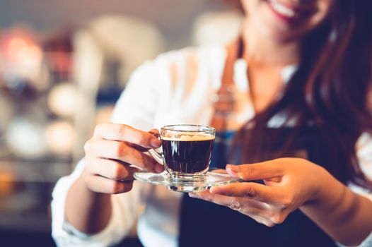 Closeup of coffee cup with beautiful Asian woman barista background for making coffee to serving to customer. Job and occupation. Food and drink beverage. Coffee shop and Cafe. Business and restaurant