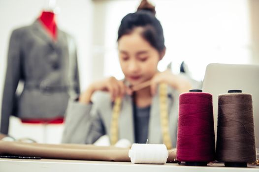 Closeup of colorful thread with fashion designer background in workshop studio. Stylish fashionista woman creating new cloth design collection. Tailoring and sewing People lifestyle and occupation