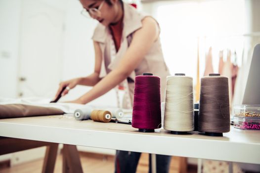 Closeup of colorful thread with fashion designer background in workshop studio. Stylish fashionista woman creating new cloth design collection. Tailoring and sewing People lifestyle and occupation