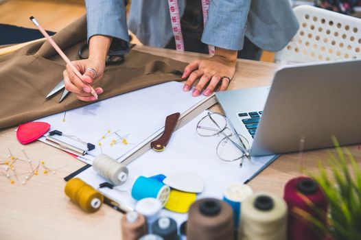 Closeup of attractive female fashion designer hand working in home office workshop. Stylish fashionista woman creating new cloth design collection. Tailoring and sewing People lifestyle and occupation