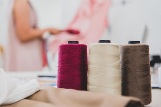 Closeup of colorful thread with fashion designer background in workshop studio. Stylish fashionista woman creating new cloth design collection. Tailoring and sewing People lifestyle and occupation