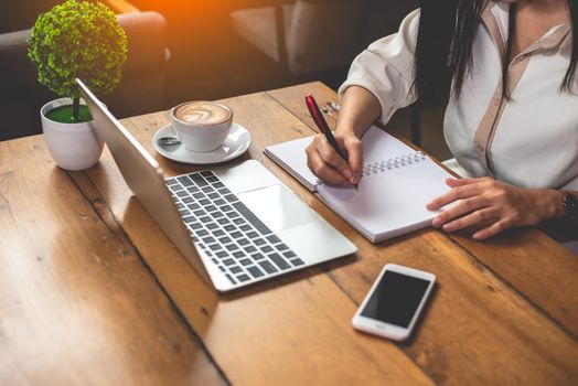 Close up of business woman working with documents and laptop in office. Business and Lifestyles concept. Entrepreneur and Freelance theme. Selective focus on coffee cup