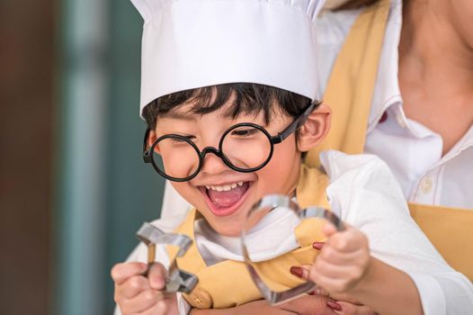 Cute little Asian happy boy interested in cooking with mother funny in home kitchen. People lifestyles and Family. Homemade food and ingredients concept. Two people baking Christmas cake and cookies