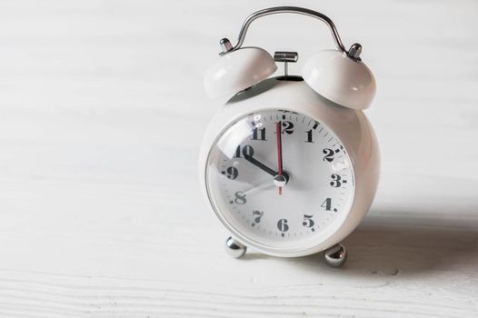 White clock on wooden table. Object and electronics concept.