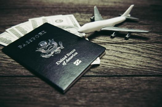 Top view of tourist planning props and travel accessories with American passport, airplane and US dollar banknote money on old wooden background. Holiday and vacation. Tourism long weekend concept.