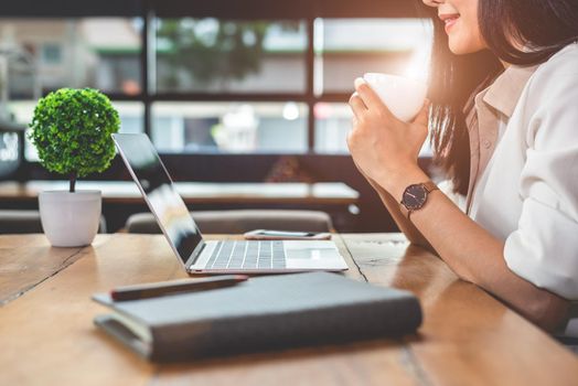 Asian working woman using laptop and drinking coffee in cafe. People and lifestyles concept. Technology and business theme. Freelance and occupation theme. Workaholic in overnight concept.