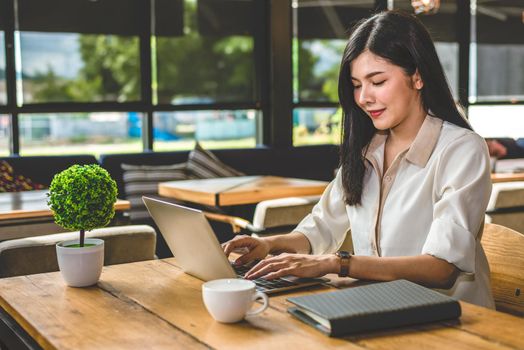 Asian woman working with laptop in coffee shop. People and Lifestyles concept. Outdoors working and freelance theme.
