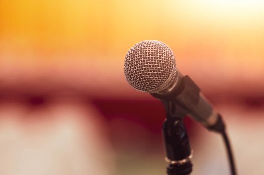 Closeup of microphone on abstract blurred background speech in seminar convention hall room and light as guest and conference speaker on podium. Workshop event and Entertainment broadcast concept.