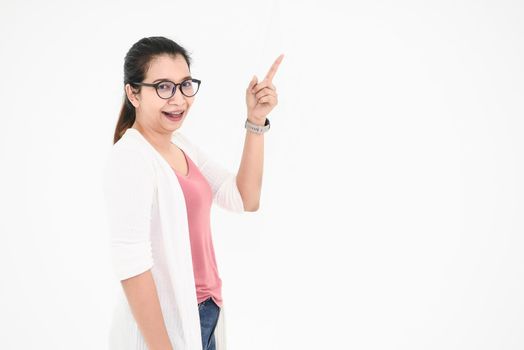 Asian woman posing and pointing finger at blank space with casual outfit and eyeglasses in happy mood on white isolated background. People beauty and portrait concept. Teacher or Professor acting.