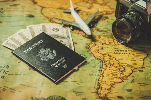 Tourist planning props and travel accessories with American passport, airplane, digital camera and US dollar banknote money on old grunge style map. Holiday and vacation. Tourism long weekend concept.
