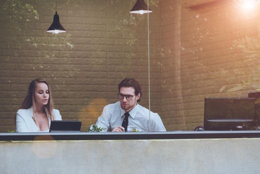 Two men and women work together in clear office with tree and nature reflection on transparent glass. Business people and Occupation concept.