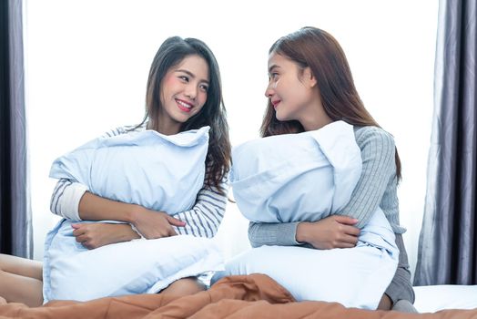 Two Asian Lesbian looking together in bedroom.Beauty concept. Happy lifestyles and home sweet home theme. Cushion pillow element and window background.